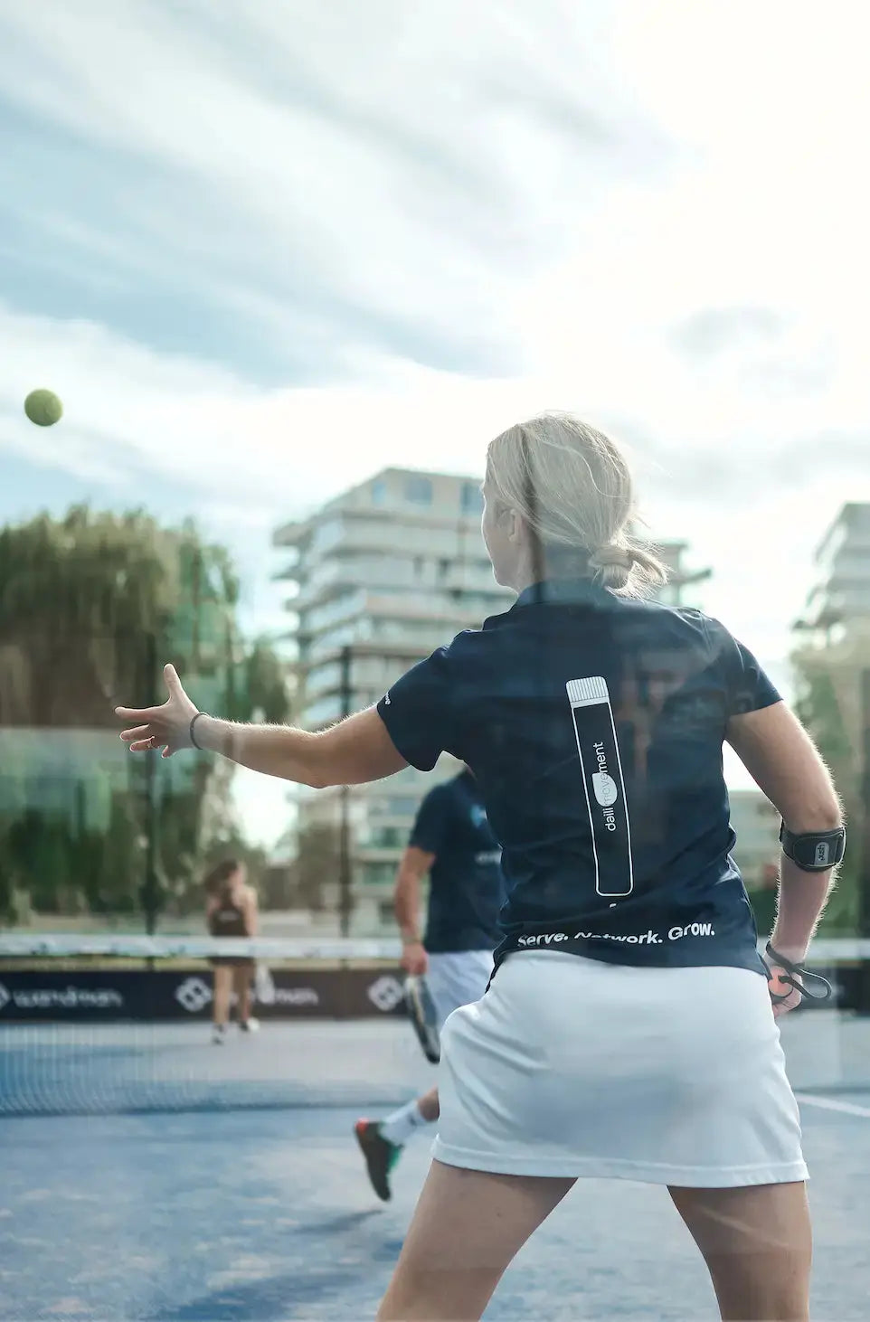 Vrouw op de padelbaan die reikt naar een bal, ter illustratie van soepel bewegen en het belang van dagelijkse mobiliteit in de winter.