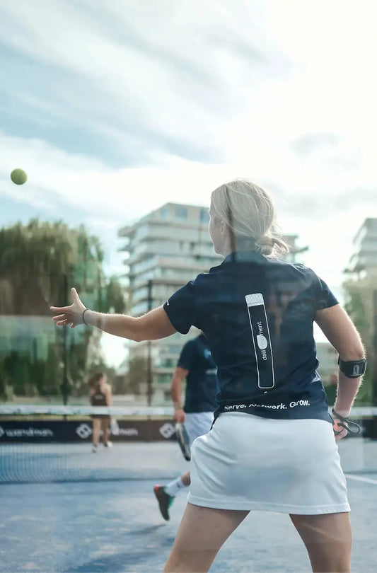 Vrouw op de padelbaan die reikt naar een bal, ter illustratie van soepel bewegen en het belang van dagelijkse mobiliteit in de winter.