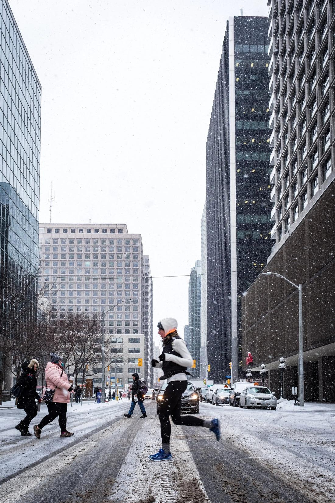 Persoon in sportkleding die in de winter door een drukke stadsstraat loopt, als voorbeeld van bewegen op een drukke dag.