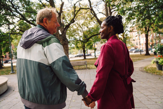 Ouder koppel wandelt hand in hand door een park, als symbool voor vlot blijven bewegen en actief ouder worden.