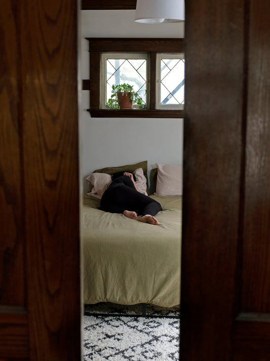 Persoon ligt ontspannen op bed in een rustige slaapkamer, symbool voor een kalme avondroutine.