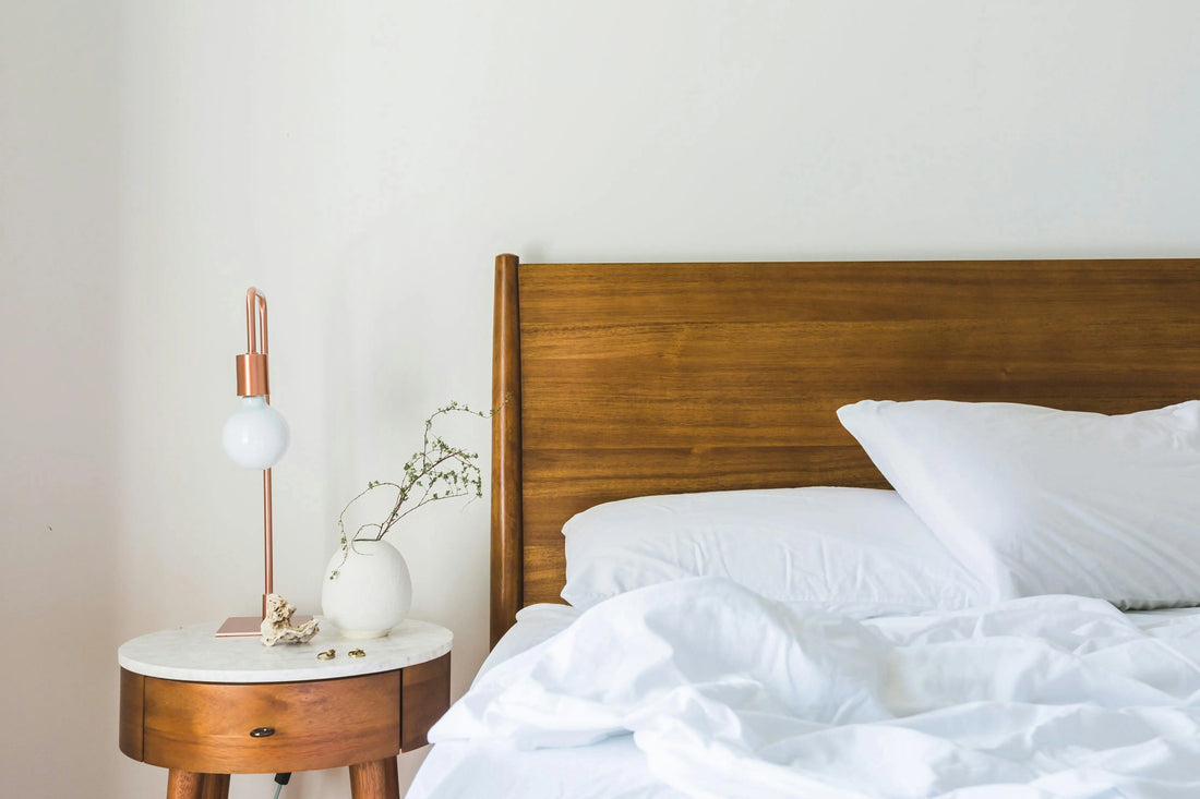 Rustige slaapkamer met opgemaakt bed en nachtkastje, symbool voor slaap, herstel en natuurlijke rustmomenten