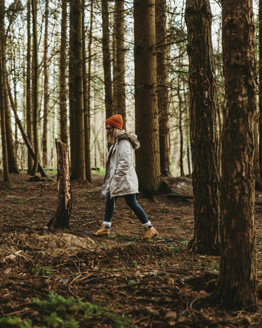 Persoon wandelt in een donker bos, wat helpt om het energieniveau verhogen en energie als dagen korter worden te ondersteunen.
