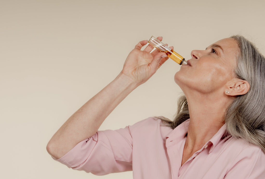 Persoon die een vloeibaar supplement inneemt als onderdeel van een dagelijkse beauty routine.